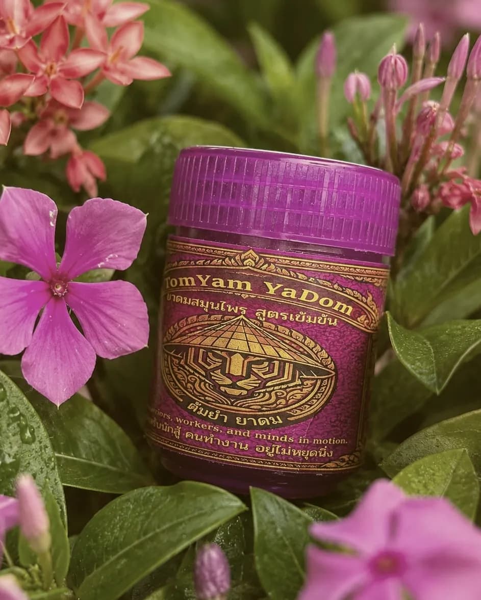 Serenity Thai herbal inhaler with purple cap among pink garden flowers